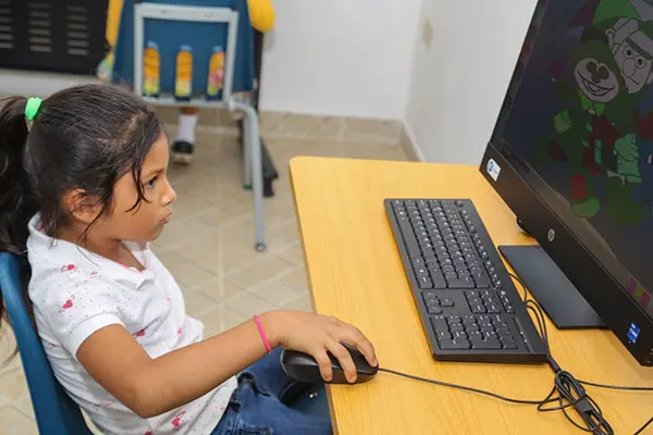Niña aprendiendo con una computadora en una Infoplaza